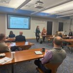 Claire Aiello & Erin Koshut present information to company leaders in Cummings Research Park about the 2026 races.
